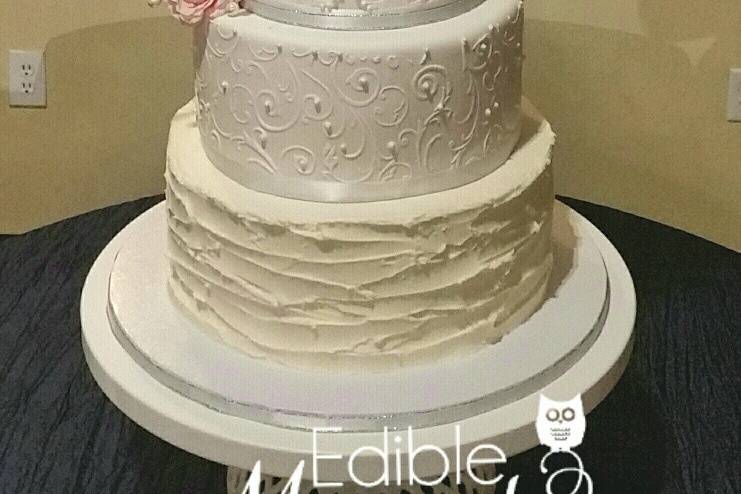 5-tier wedding cake.  Middle tier is an 8 inch double barrel focal tier with bridal monogram and stencil design adorned with Swarvoski crystals & pearls.  Silver dragees accent the top rim of 3 tiers.  Bottom tier is designed with White Chocolate... delicious !