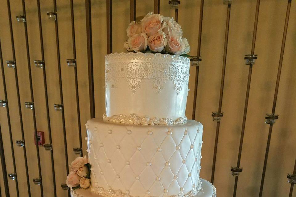 4-tier fondant design with quilting & pearl accents.  Edible lace to coordinate with the bride's dress.