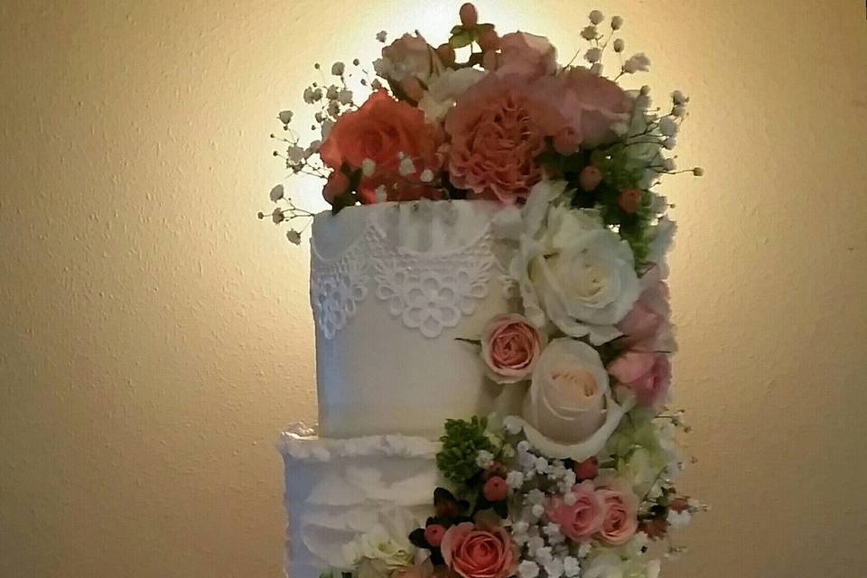 A butter cream beauty accented with edible lace on the top and bottom tiers.  Monogram.  Fresh flower cascade.