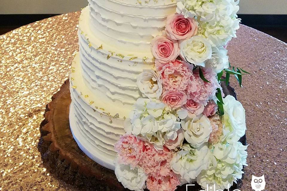 Butter Cream wedding cake with golf leaf accents.  We love the wood tiers!  Fresh flower cascade.