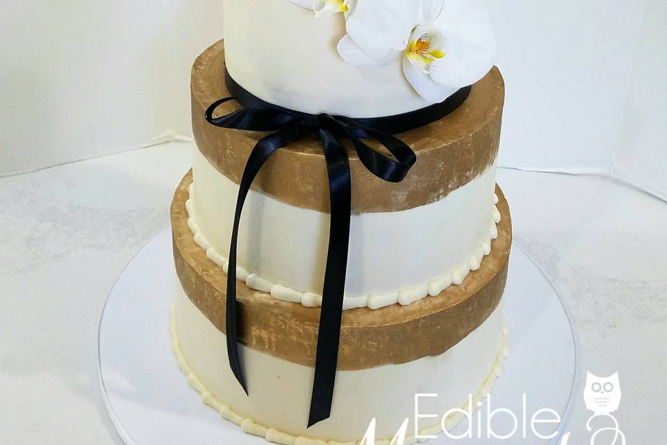 Butter Cream Beauty with hand-painted gold trim, fresh Orchids, and black ribbon accent