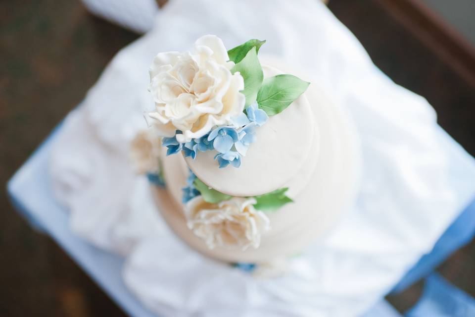 Garden roses (ivory), with blue hydrangeas and green foliage all handcrafted from sugar.