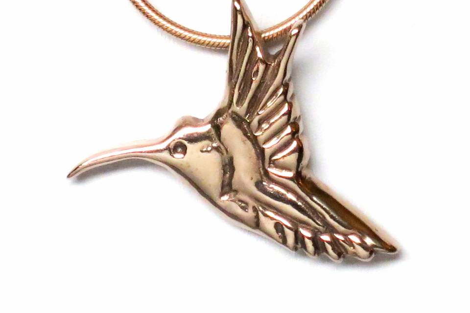 18K Gold Vermeil hummingbird necklace is delicate, feminine and festive. It measures 1 1/2 inches wide by 1 1/4 inches high. The hummingbird is suspended with a ring on reverse and showcased on an 18-inch gold finished brass snake chain with a  spring-ring clasp. Symbolism: The hummingbird symbolizes joy and playfulness as well as independence. It has the characteristics of being well traveled, displaying resiliency by covering great distances tirelessly. It reminds us to enjoy the simple pleasures and to experience the sweet nectar of life.