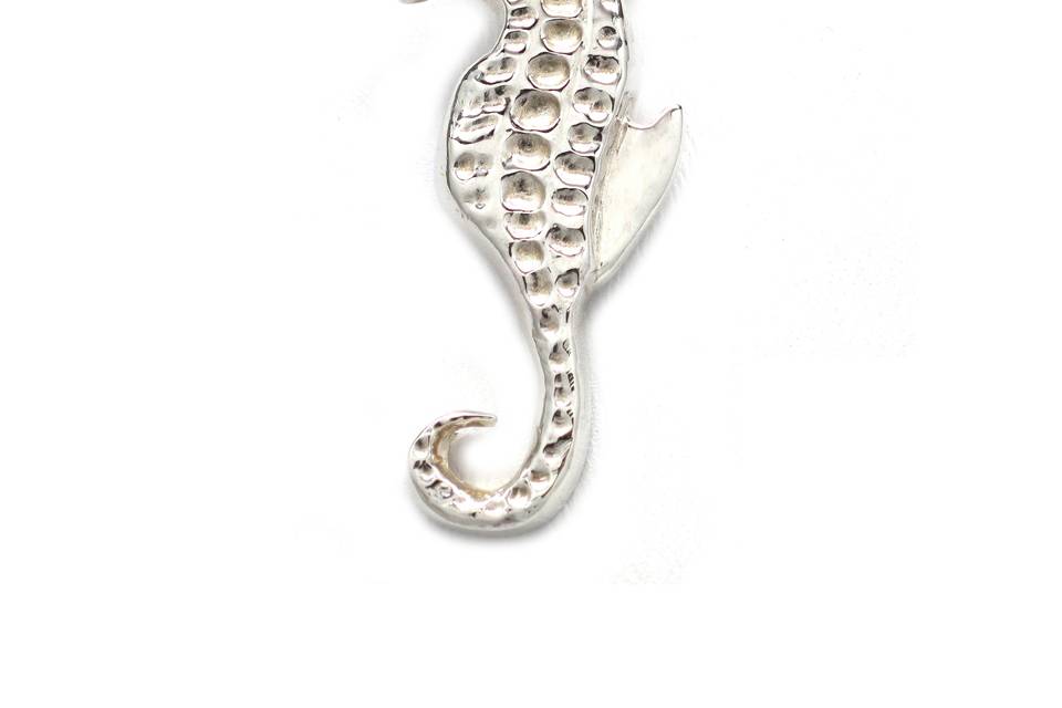 The sterling silver seahorse necklace is a high fashion piece that connotes a stunning and impactful appearance.  The seahorse necklace has an organic presence with trim contours and a timeless profile. It measures ¾ inches wide by 1 ½ inches high. The seahorse is suspended with a ring on reverse and showcased on an 18-inch sterling silver snake chain with a lobster claw clasp.   Symbolism: The ancient Greeks and Romans considered the seahorse as a symbol of strength and power.  The Chinese referred to the seahorse as a sea dragon, and as such they were revered for their power as a good luck symbol. Sailors also believe the seahorse to be a good luck charm.