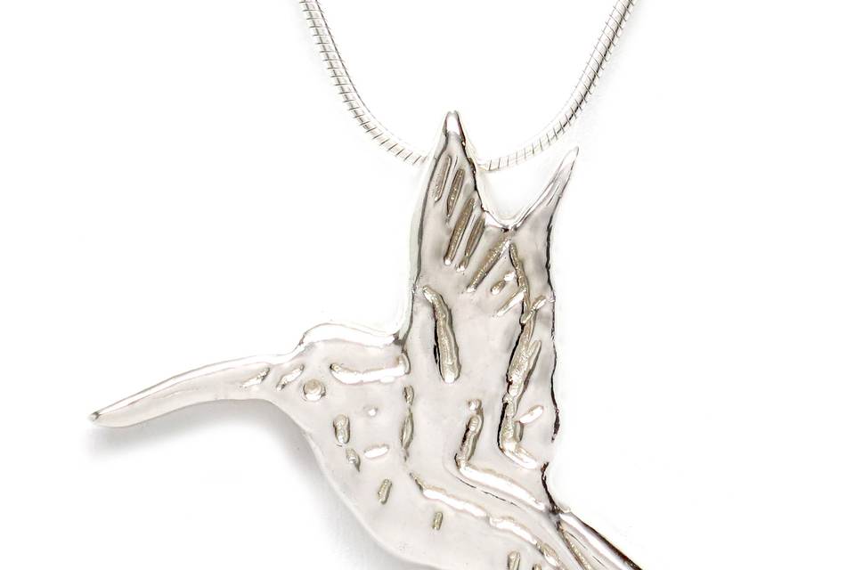 Sterling Silver Hummingbird necklace is delicate, feminine and festive. It measures 1 1/2 inches wide by 1 1/4 inches high. The hummingbird is suspended with a ring on reverse and showcased on an 18-inch gold finished brass snake chain with a  spring-ring clasp. Symbolism: The hummingbird symbolizes joy and playfulness as well as independence. It has the characteristics of being well traveled, displaying resiliency by covering great distances tirelessly. It reminds us to enjoy the simple pleasures and to experience the sweet nectar of life.