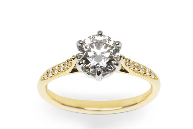 Our 50th Anniversary is truly a Jublilee, and we designed a diamond ring to capture the excitement. A 1.22 carat diamond nestles in a six prong platinum cathedral setting. Its beauty is highlighted by a graceful selection of round brilliant cut bead set diamonds set into the 18k yellow gold band. We didn’t forget to set a special golden sapphire on the underside of the diamond, as a nod to our “Golden Anniversary” and a hidden treasure for you. Contact us to discuss “one of a kind” possibilities. #030508