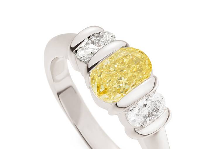 Our three stone Ridge ring is perfect for the woman with an active lifestyle that wants her diamonds to be the center of the show. This all platinum Ridge Ring features a rare Fancy Intense Yellow oval diamond center with oval white diamond sides. #010418