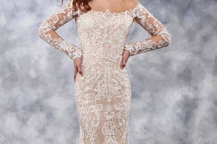 Tulle and lace applique bridal sheath gown features illusional off-the-shoulder neck line, long fitted sleeves, sheer back with button details, and sweep train.