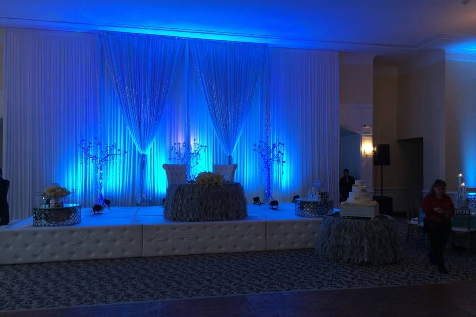 Beautiful ivory drape backdrop with tiffany blue uplighting.