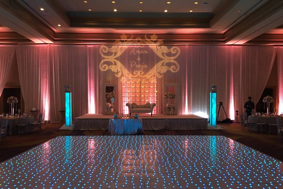 Starlight dance floor, uplighting, draping, moving head towers, and monogram.