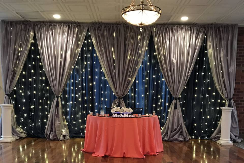 Navy and silver draping for the sweetheart table with twinkle lights.