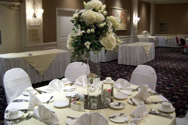 Tall centerpieces add drama and height to an intimate reception, complete with white chairs covers with ivory organza bows.