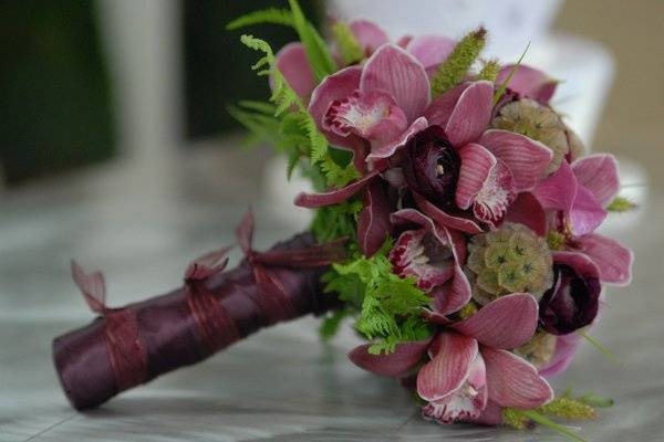 Burgundy bouquet with cymbidium orchid, calla lily, ranunculus, scabiosa pods and fern