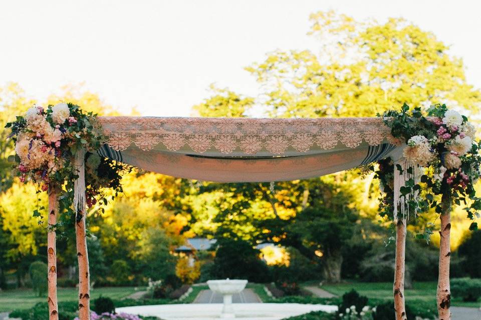 Birch pole chuppah with autumnal floral accents for garden ceremony