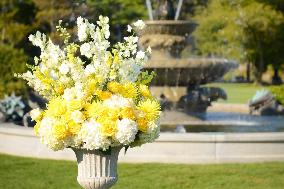 Classic urn arrangement with yellow and white summer  flowers for outdoor ceremony