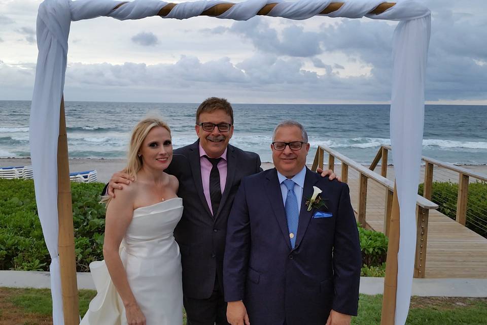 Newlyweds and the officiant by the beach
