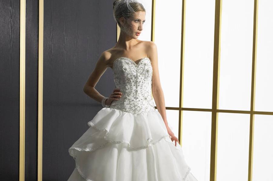 Style D8028
A silky organza ball gown with soft flowing tiers throughout the skirt. Each layer is trimmed with lace and beading. The bodice features a sweetheart neckline and curved basque waist accented with Swarovski crystals, beading, and silver embroidery.