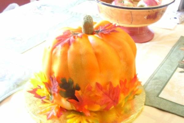 Pumpkin Spice cake with cream cheese frosting, fondant covered with silk fall leaves scattered around pumpkin