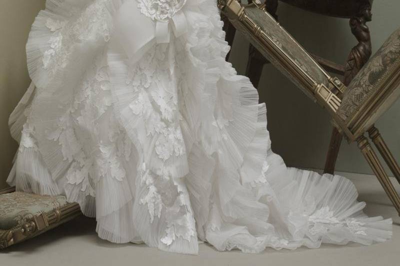 Gown features hand-embroidered leaves on bodice, pleated swirls on flared skirt and beading.