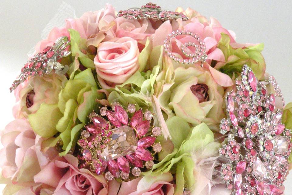 Glamourous brooch jeweled bouquet studded with rhinestone and crystal brooches, gathered in a gold metal bouquet holder. Shown here in pink but available in other colors