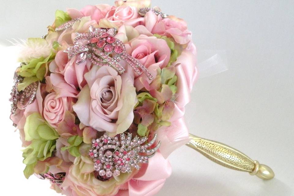 Glamourous brooch jeweled bouquet studded with rhinestone and crystal brooches, gathered in a gold metal bouquet holder. Shown here in pink but available in other colors