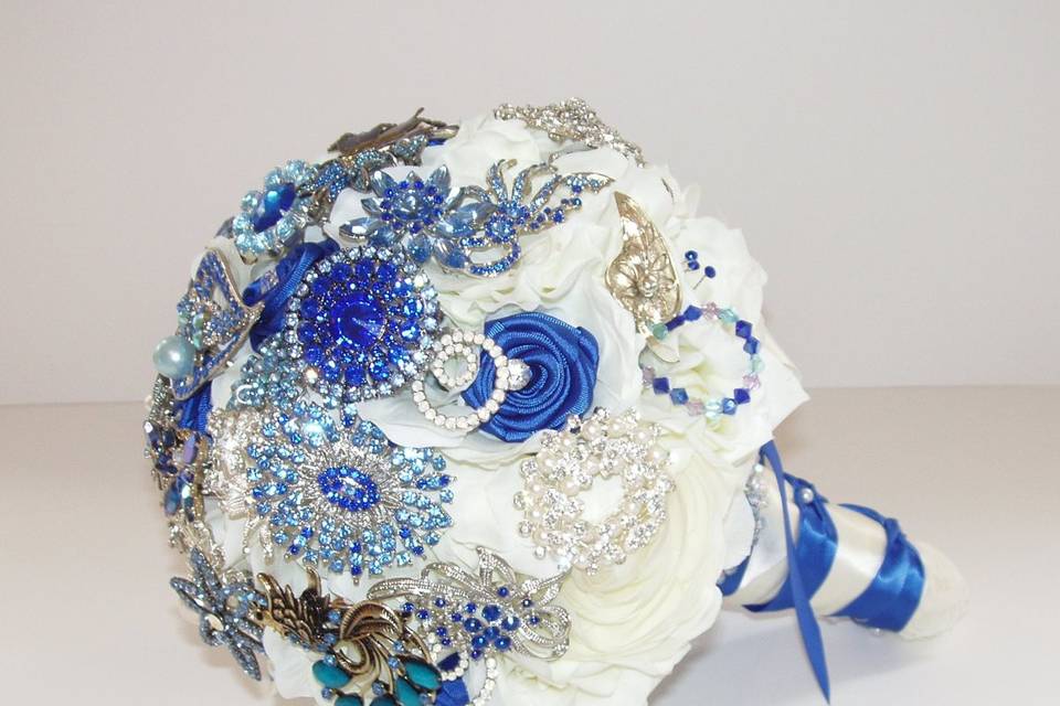 Glamourous brooch jeweled bouquet studded with rhinestone and crystal brooches, with white silk hydrangea and roses and sapphire satin ribbon roses. Shown here in white and sapphire but available in other colors