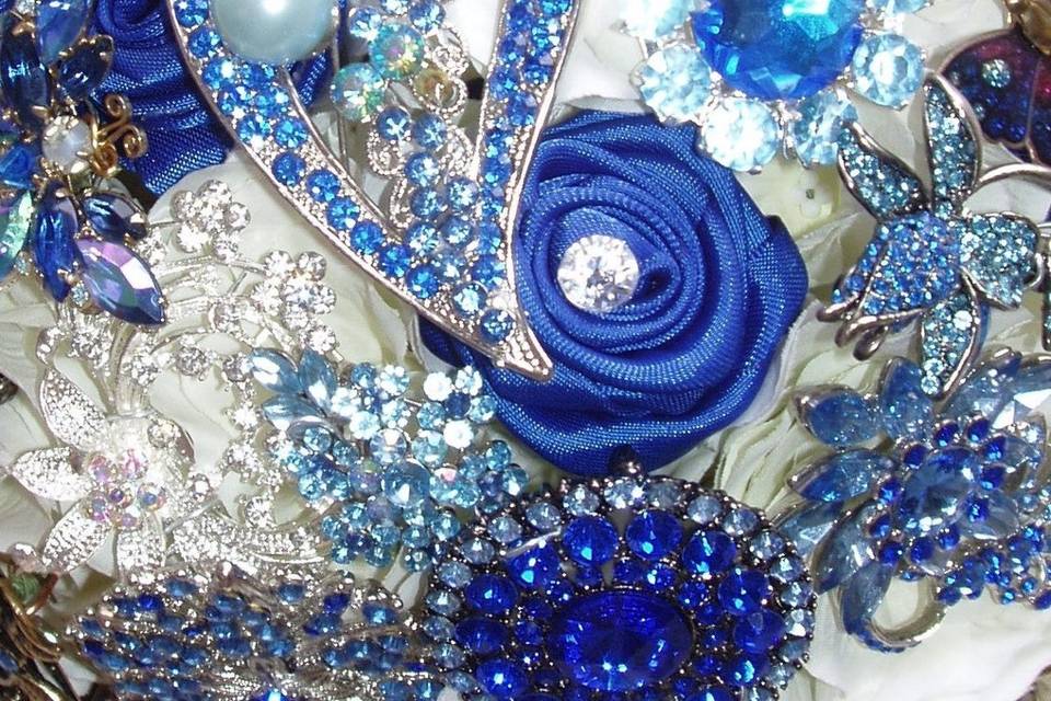 Glamourous brooch jeweled bouquet studded with rhinestone and crystal brooches, with white silk hydrangea and roses and sapphire satin ribbon roses. Shown here in white and sapphire but available in other colors