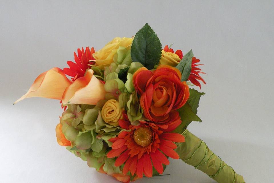 Lovely and romantic quality silk bouquet created with orange/yellow calla lilies, green hydrangea, orange ranuculus and orange gerbera daisies. The handle is wrapped in an irridescent green ribbon with a decorative green wire overlay.
This bouquet is available in other colors.