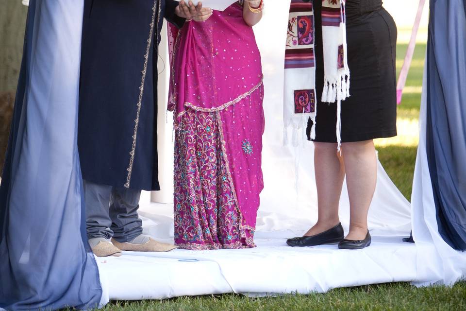 Newlyweds and the officiant under the arch