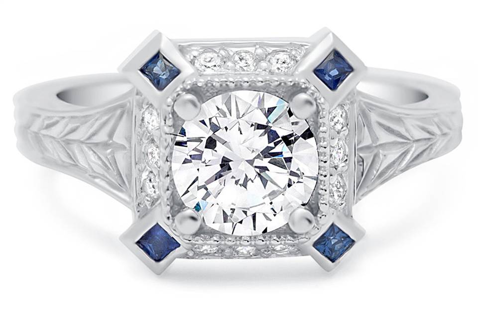 Vintage inspired engraved ring has a round diamond center and 4 princess cut blue sapphires in each corner. So regal!