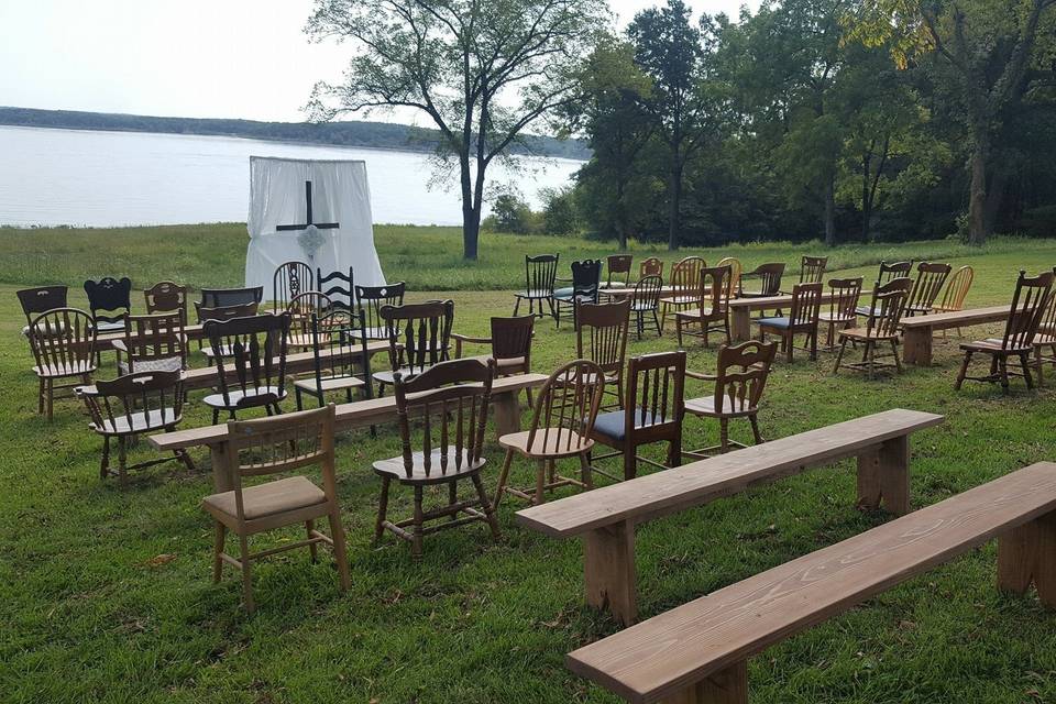 Lakeside ceremony with a mixture of antique seating and wooden benches