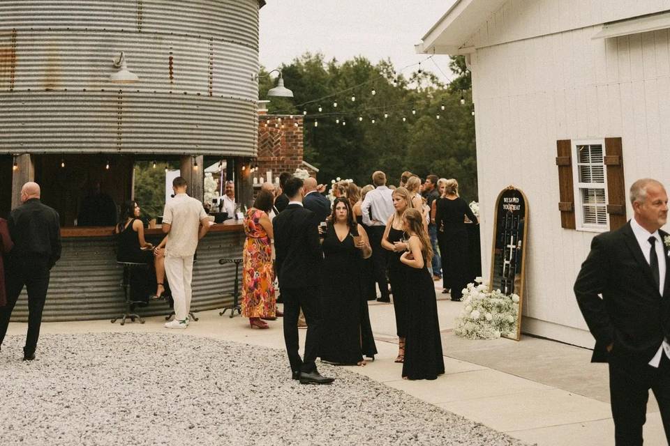 Guests at cocktail hour on the patio between the Silo Bar and the barn