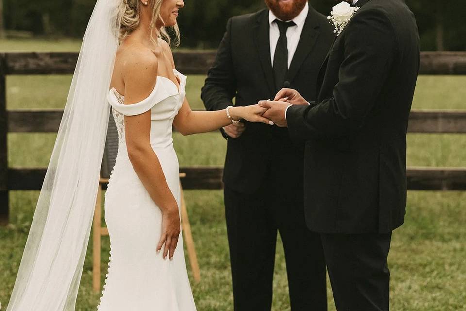 A bride and groom exchanging vows during their ceremony on the lawn