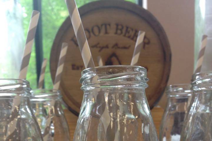 Root beer and orange cream soda served in old fashion bottles with paper straws.  The jars are a favor your guests can keep.