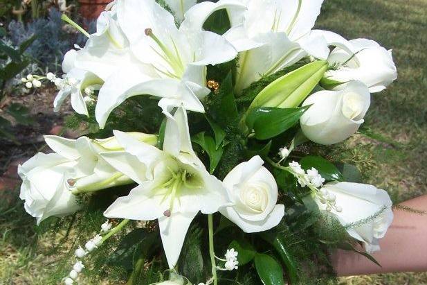 Cascading bouquet with oriental casa blanca lilies, ivory roses, and dainty lily of the valley flowers gives this bouquet a beautiful English feel.