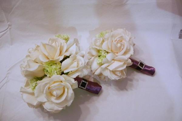 Ivory Real Touch Roses with green snowball hyndrangea blooms.  The Stems are wrapped in purple satin ribbon and accented with a rhinestone buckle.