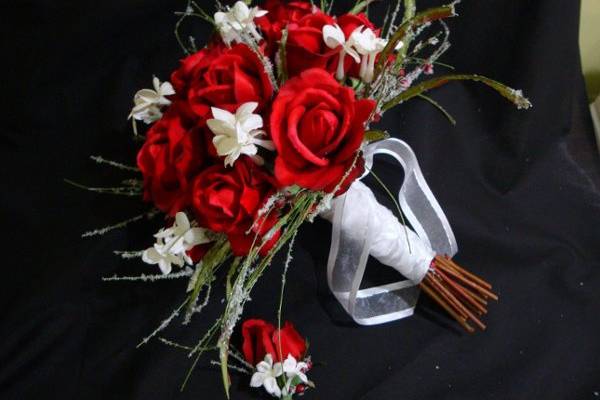 A beautiful holiday, winter bouquet with Red real touch roses, stephenosis blooms and frosted christmas greens.  The stems are wrapped in white satin and sheer ribbon.  This was a very popular bouquet this winter!