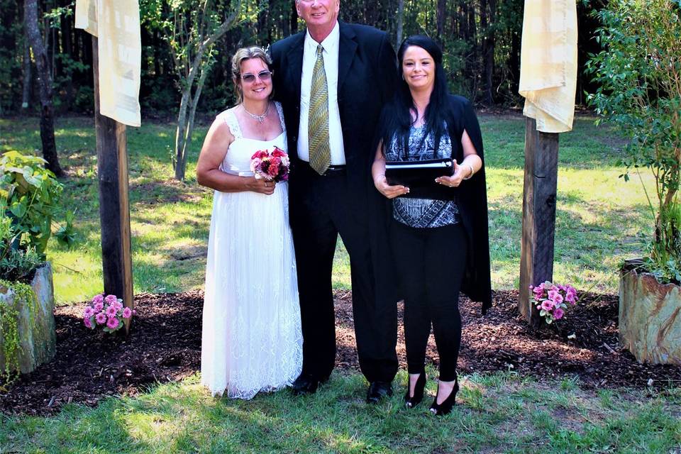 Newlyweds and officiant under the arch