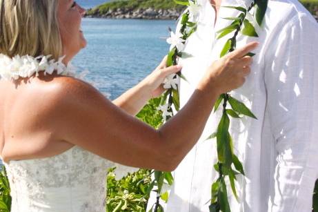 bride puts on grooms lei