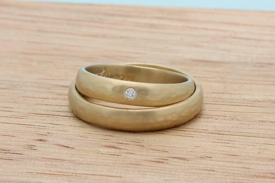 Classic half round bands in recycled 18k yellow gold. With a hammered texture and a flush set diamond.