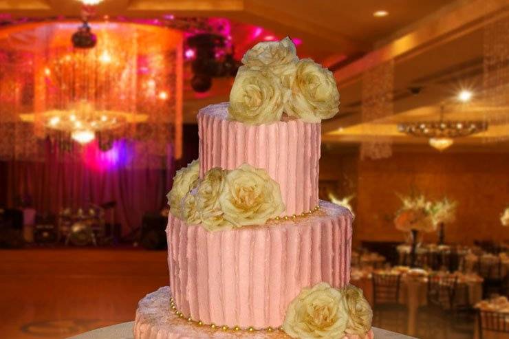 Tired of fondant? Here's one of our wedding cakes covered with soft pink Italian Meringue Buttercream in a vertical fluttering fringe pattern, then framed with gold-dusted Parisian Ivory Roses and dots of gold dragées. Very feminine and enchanting!