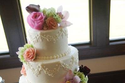 Vanilla/almond cake with almond cream filling.  Ivory buttercream icing with piping and fresh flowers.