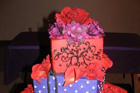 Red and purple buttercream with black fondant accents. Top and bottom tiers are faux!