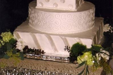 Round and square cakes iced in buttercream with fondant accents painted with shimmer lustre dust.  Fresh flowers.