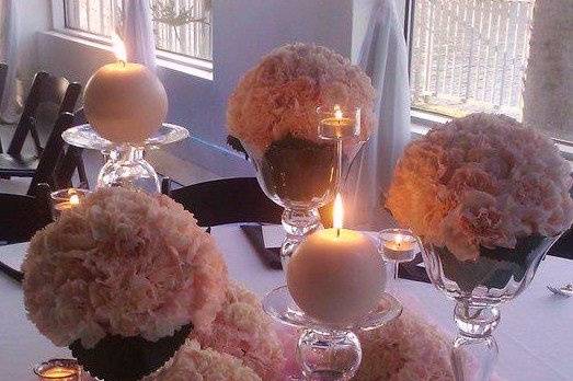 Picture courtesy Julie Cate Photography.  Floral Design by Garden Gate Florals.  6 round pomanders filled with peachy/pink carnations sitting on the table and in different heights vases. Several tall candles and silver votives with a sheer blush underlay.  Table #15