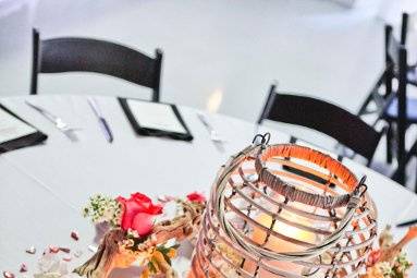 Table #14...Large wicker lantern with 8 inch candle surrounded by driftwood with fresh flowers such as roses, hydrangea, greenery and waxflower.  Added silver votives give a romantic touch.  Pic by DanielleNichol Photography.