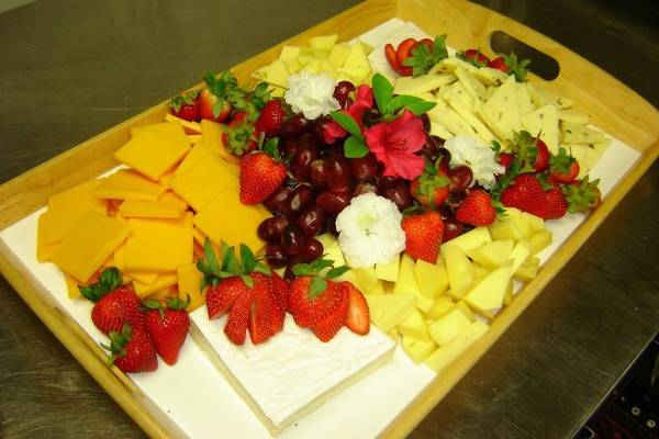 A delicious mulit-cheese platter garnished with grapes and strawberries.