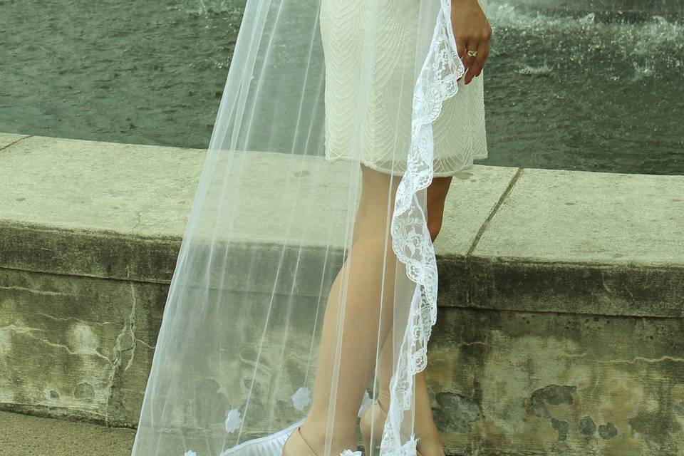 white single tier floor length tulle veil with chantilly lace edging n the sides finished with pleated woven ruffle bottom and white floral appliques.