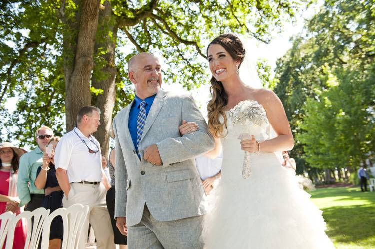 A happy father walking his daughter down the aisle