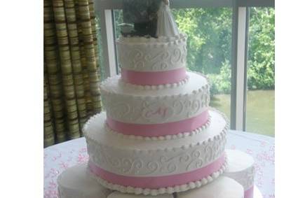 Buttercream tier cake with six individual cakes.  Accent with pink ribbon.